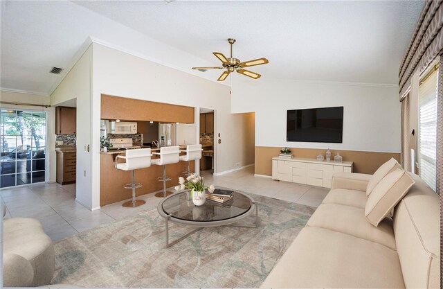 living room with crown molding, ceiling fan, vaulted ceiling, and light tile patterned floors