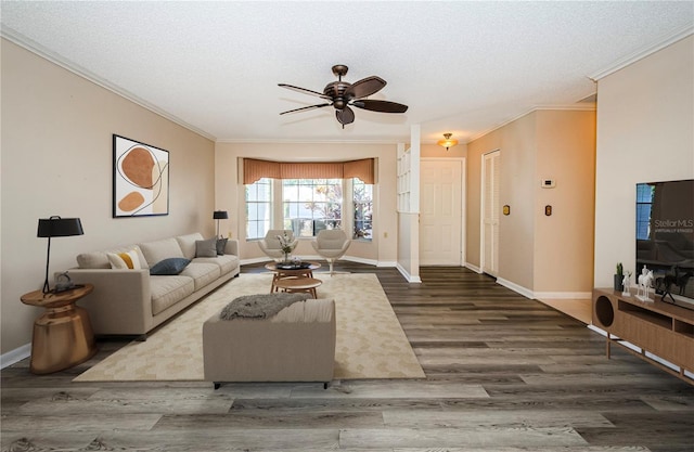 living room with ceiling fan, ornamental molding, dark hardwood / wood-style flooring, and a textured ceiling