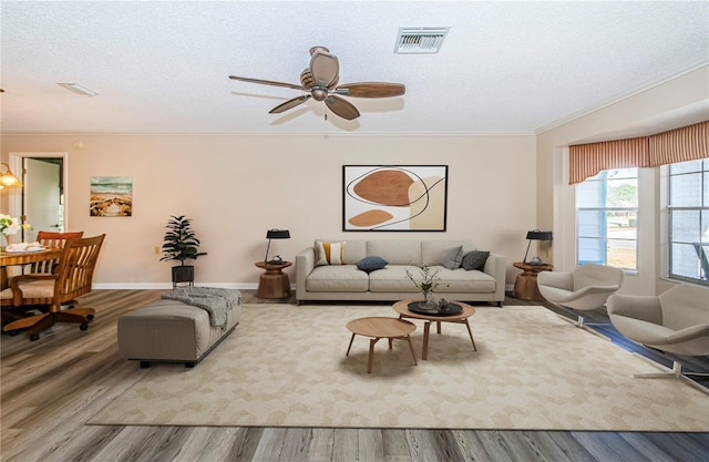 living room featuring ceiling fan, crown molding, wood-type flooring, and a textured ceiling