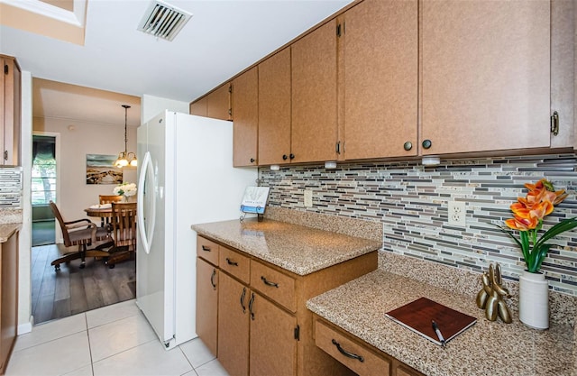 kitchen featuring tasteful backsplash, crown molding, decorative light fixtures, light tile patterned floors, and white fridge