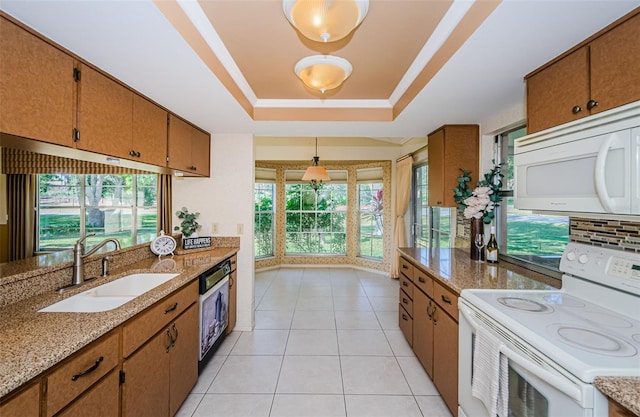 kitchen featuring sink, white appliances, light stone countertops, decorative light fixtures, and a raised ceiling