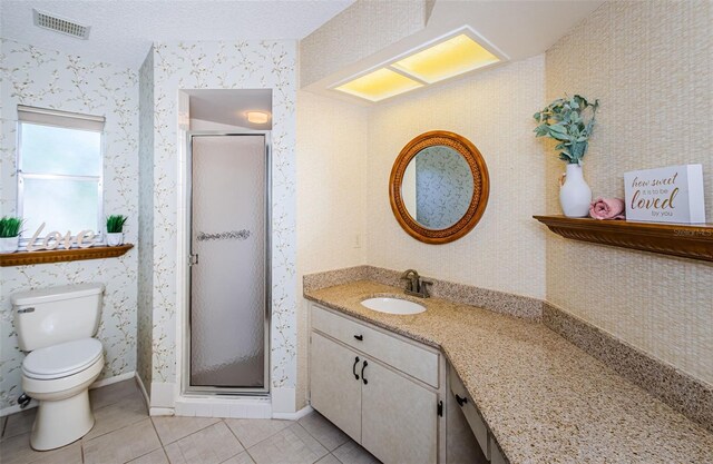 bathroom with tile patterned floors, toilet, a textured ceiling, vanity, and a shower with door