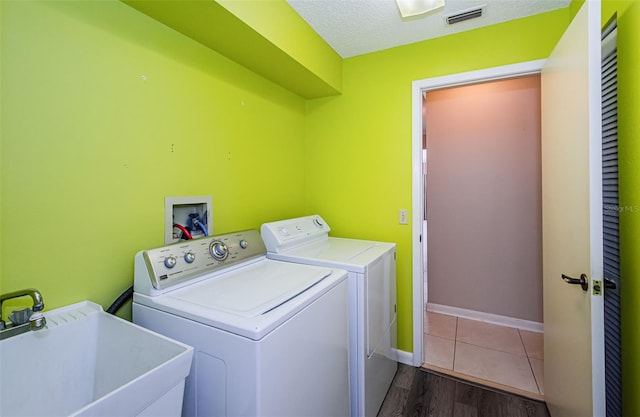 laundry room featuring sink, washer and clothes dryer, dark hardwood / wood-style floors, and a textured ceiling