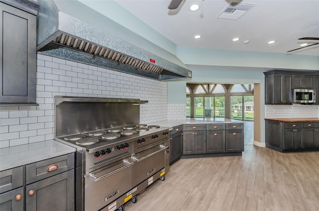 kitchen with tasteful backsplash, ceiling fan, kitchen peninsula, stainless steel appliances, and light hardwood / wood-style flooring