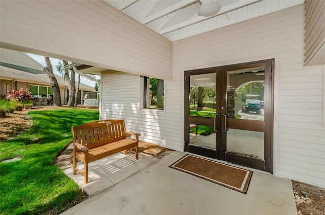 property entrance featuring french doors, ceiling fan, a yard, and a patio area