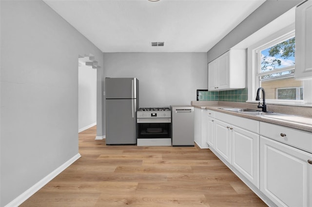 kitchen featuring sink, backsplash, stainless steel appliances, light hardwood / wood-style floors, and white cabinets