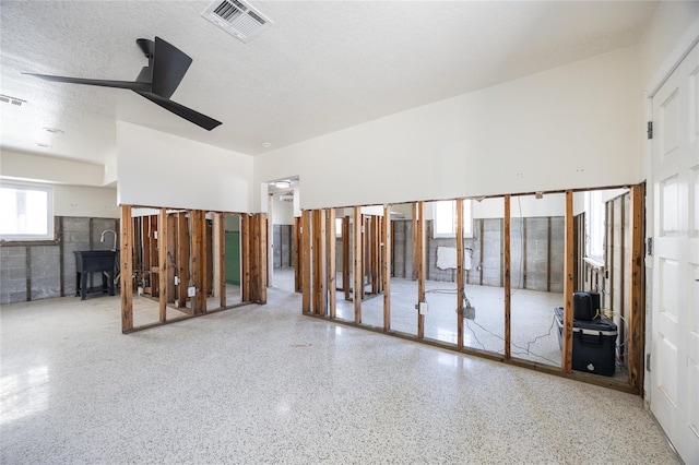 unfurnished room with ceiling fan and a textured ceiling