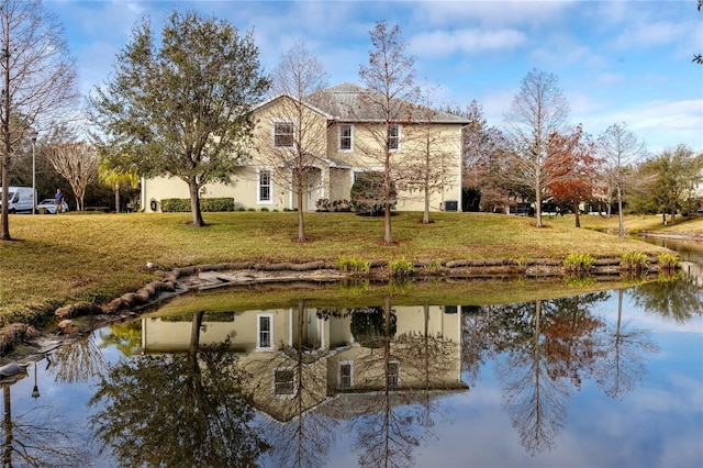 back of property featuring a water view and a lawn