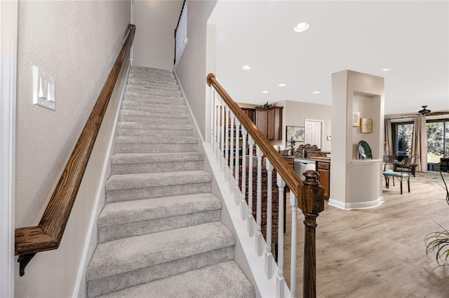 staircase featuring ceiling fan and wood-type flooring