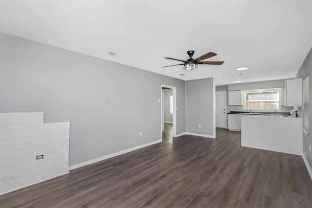 unfurnished living room featuring dark hardwood / wood-style flooring, sink, and ceiling fan