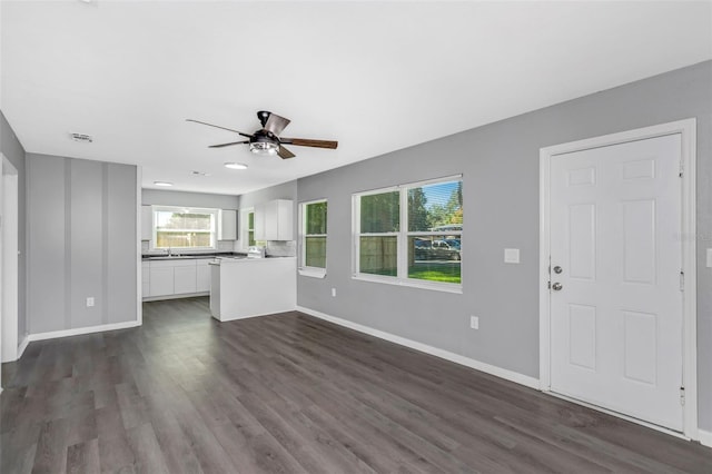 unfurnished living room with dark hardwood / wood-style floors and ceiling fan