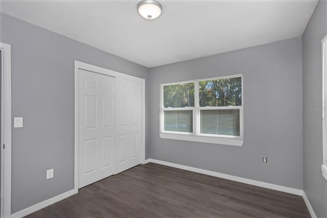 unfurnished bedroom with dark hardwood / wood-style flooring and a closet