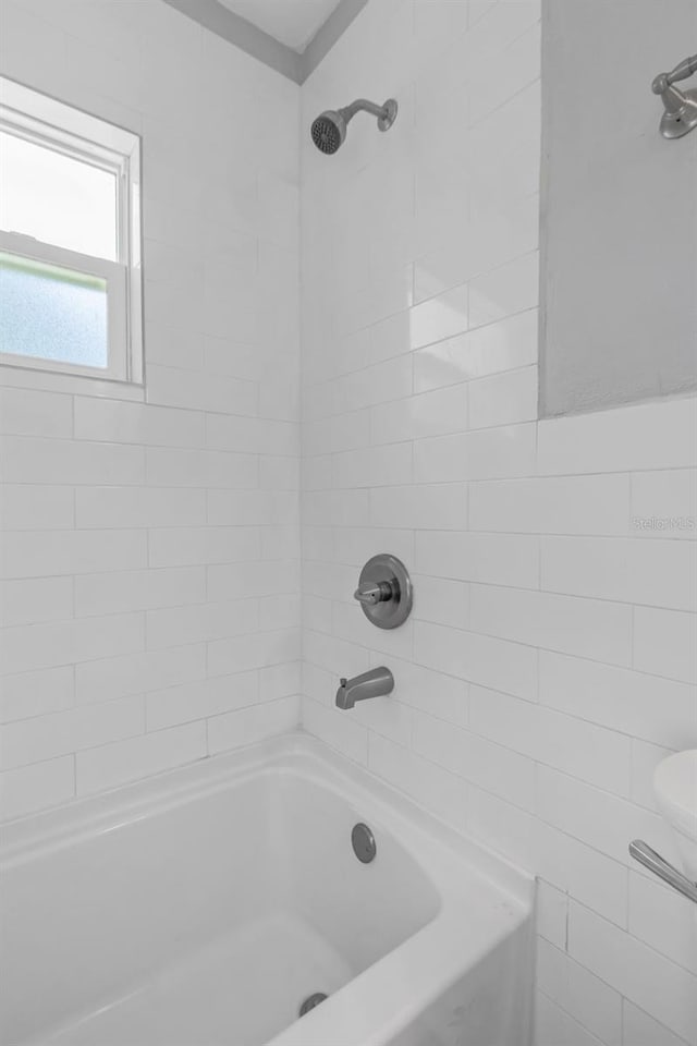 bathroom with tiled shower / bath combo and toilet