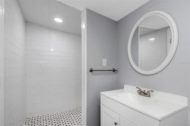 bathroom featuring a tile shower and vanity