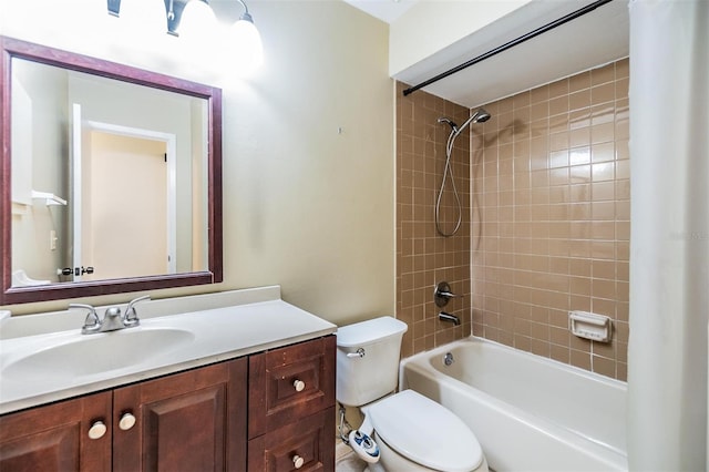 full bathroom featuring tiled shower / bath, vanity, and toilet