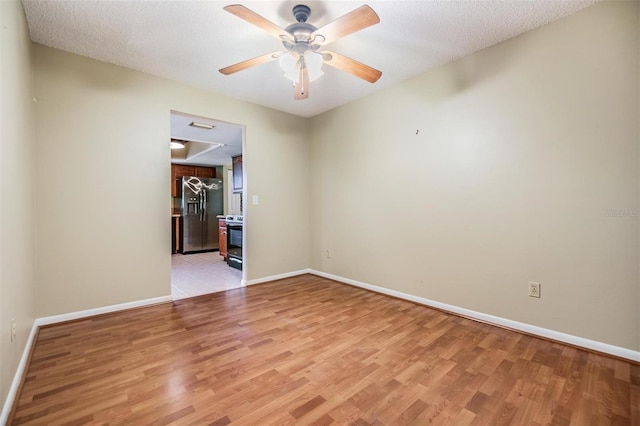 empty room featuring ceiling fan, light hardwood / wood-style floors, and a textured ceiling