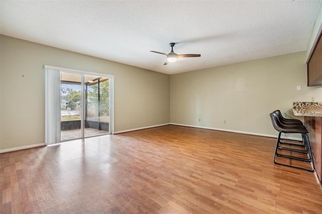 unfurnished living room featuring a textured ceiling, ceiling fan, and light hardwood / wood-style floors