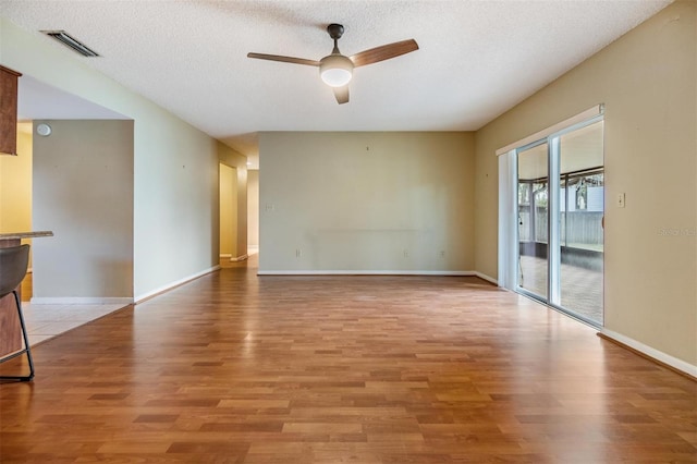 unfurnished room with ceiling fan, a textured ceiling, and light wood-type flooring