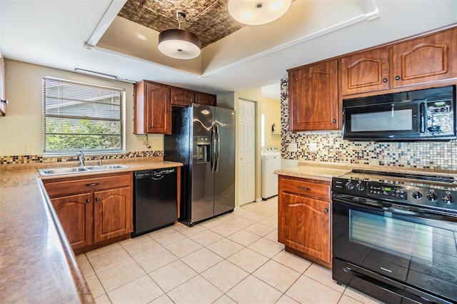 kitchen with light tile patterned flooring, tasteful backsplash, black appliances, sink, and a tray ceiling