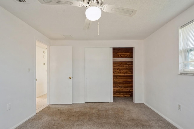 unfurnished bedroom with ceiling fan, light carpet, a textured ceiling, and a closet