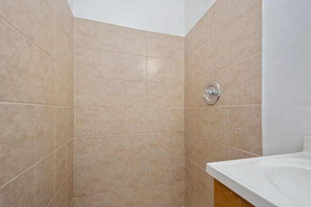 bathroom with a tile shower and vanity