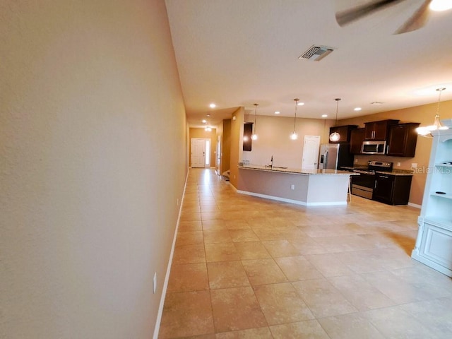 kitchen featuring pendant lighting, dark brown cabinets, ceiling fan, and appliances with stainless steel finishes