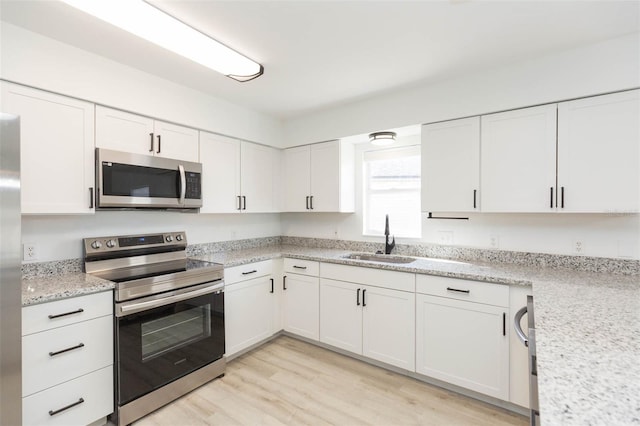 kitchen with sink, light hardwood / wood-style floors, white cabinets, and appliances with stainless steel finishes