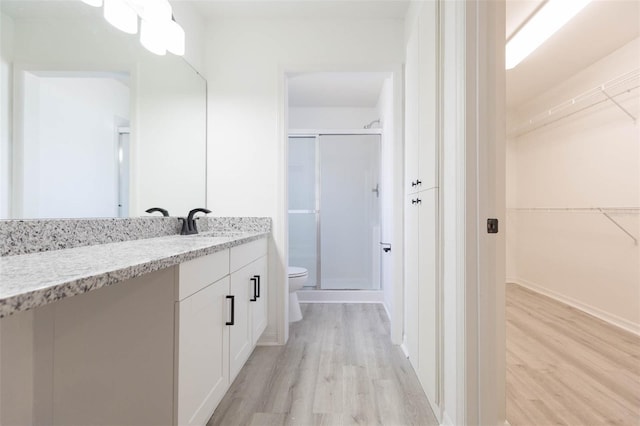 bathroom with vanity, toilet, an enclosed shower, and hardwood / wood-style floors