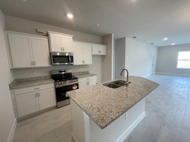 kitchen featuring sink, stainless steel appliances, an island with sink, and white cabinets