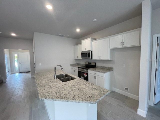 kitchen with sink, appliances with stainless steel finishes, a kitchen island with sink, light stone countertops, and white cabinets