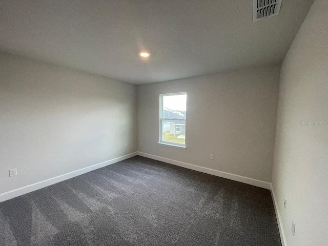 spare room with dark carpet