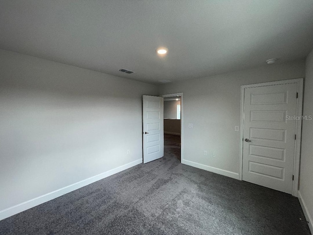 unfurnished room featuring dark carpet