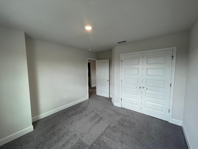 unfurnished bedroom with a closet and dark colored carpet