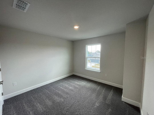 spare room featuring dark colored carpet