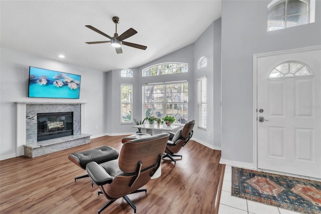 entrance foyer with a premium fireplace, wood-type flooring, ceiling fan, and high vaulted ceiling