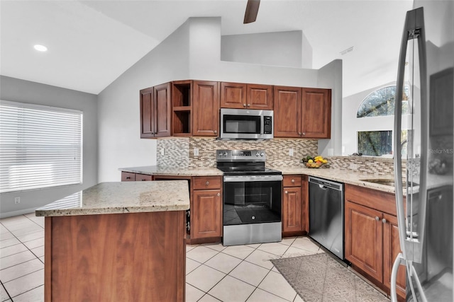 kitchen featuring a kitchen island, vaulted ceiling, appliances with stainless steel finishes, and light tile patterned floors