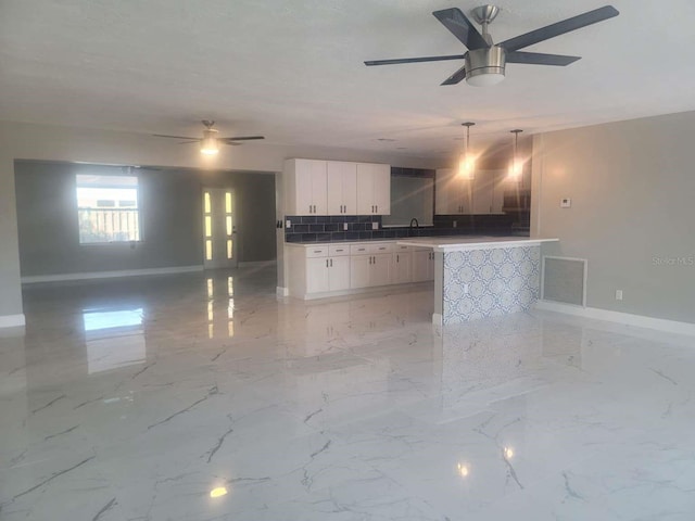 kitchen with pendant lighting, ceiling fan, decorative backsplash, and white cabinets