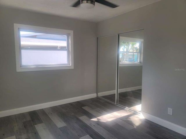 unfurnished bedroom with dark hardwood / wood-style floors, a closet, and ceiling fan