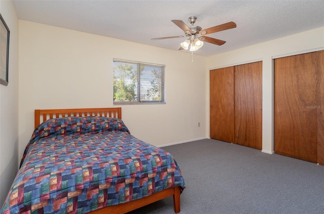 carpeted bedroom with ceiling fan, a textured ceiling, and two closets