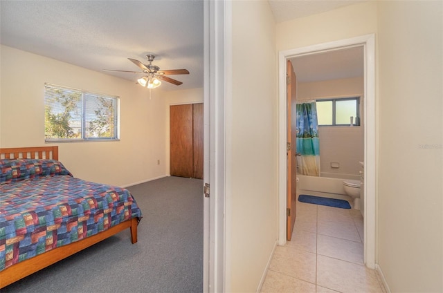 bedroom with a textured ceiling, light tile patterned flooring, ceiling fan, and ensuite bathroom