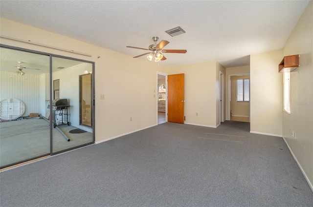 carpeted spare room with ceiling fan and a textured ceiling