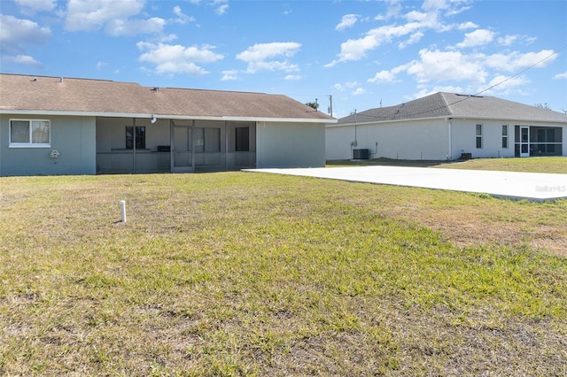 rear view of house with central air condition unit and a lawn