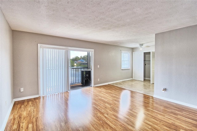 unfurnished room featuring ceiling fan, a textured ceiling, and light wood-type flooring