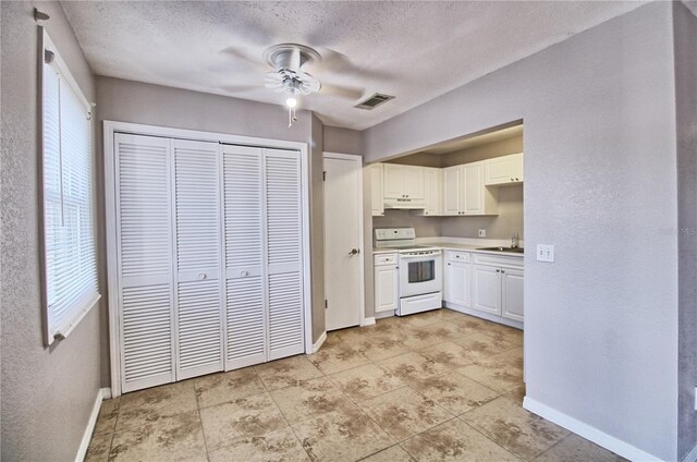13760 Orange Sunset Dr Unit 201, Tampa, FL 33618 - kitchen featuring ceiling fan, white range with electric cooktop, a textured ceiling, and white cabinets