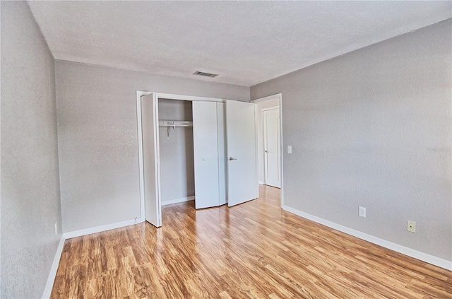 13760 Orange Sunset Dr Unit 201, Tampa, FL 33618 - unfurnished bedroom with a closet, a textured ceiling, and light wood-type flooring