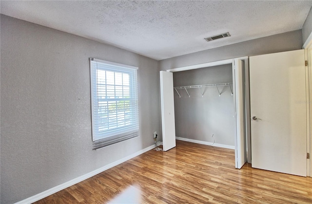 13760 Orange Sunset Dr Unit 201, Tampa, FL 33618 - unfurnished bedroom featuring a closet, a textured ceiling, and light wood-type flooring