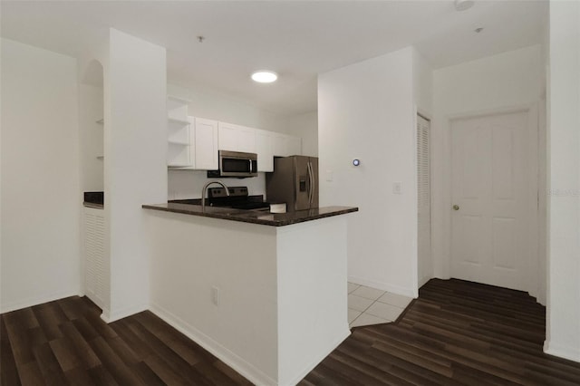 kitchen with white cabinetry, stainless steel appliances, dark hardwood / wood-style flooring, and kitchen peninsula