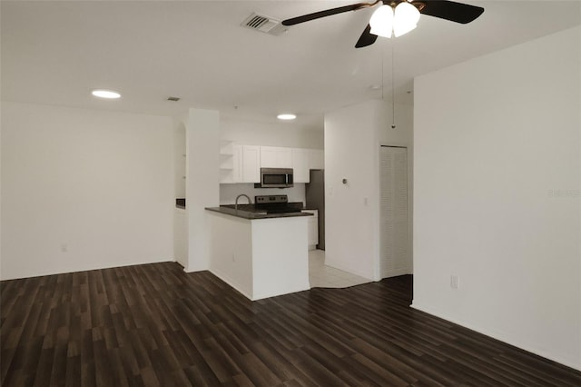 kitchen featuring kitchen peninsula, dark hardwood / wood-style floors, white cabinets, and appliances with stainless steel finishes