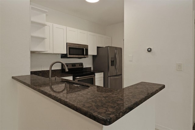 kitchen featuring stainless steel appliances, kitchen peninsula, sink, and white cabinets