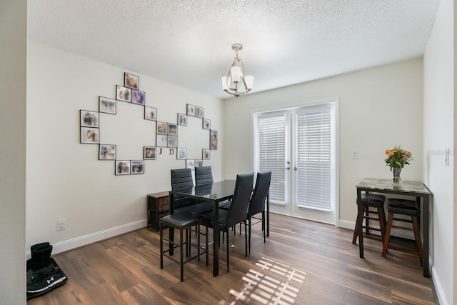 dining area with dark hardwood / wood-style floors, a notable chandelier, and a textured ceiling